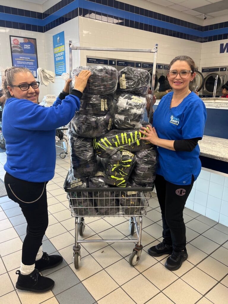 Two Drop & Dash team members with a cart of wrapped laundry orders